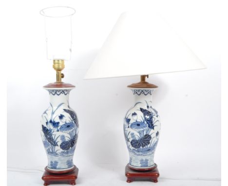 A pair of vintage 20th century ceramic pottery lamp lights. Blue and white decoration with tapering body with hardwood stand.