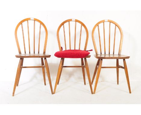 A pair of mid 20th century 1960's beech dining / kitchen chairs. In the manner of Ercol Quaker. Having an arched spindle back