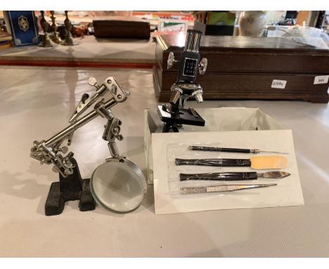 A SMALL MICROSCOPE WITH TOOLS AND A MAGNIFYING GLASS ON A STAND 