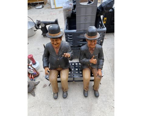 A RESIN LAUREL AND HARDY FIGURE SITTING ON A METAL BENCH 