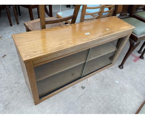 A LIGHT OAK BOOKCASE WITH GLASS SLIDING DOORS 
