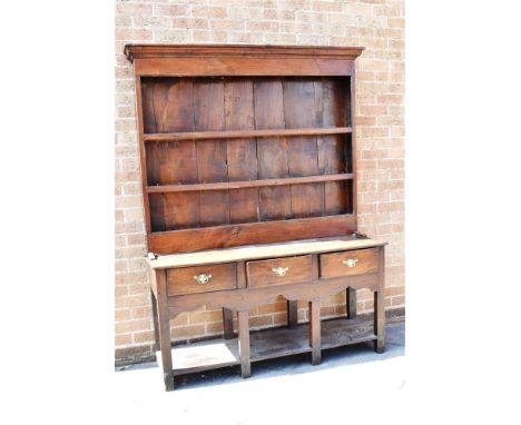 AN OAK DRESSER  the upper section with moulded cornice above three shelves, the base with three drawers and shaped apron abov