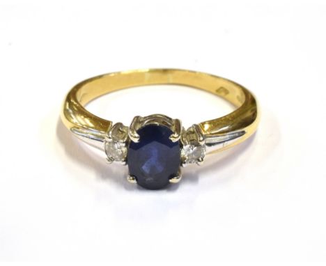 MODERN SAPPHIRE AND DIAMOND RING Central oval cut mid blue sapphire approx 7.1 x 5.2mm (estimated 1.0 carat) flanked by two 3