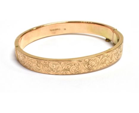 9CT ENGRAVED GOLD BANGLE 8.1mm wide scroll and foliate engraved front with plain rear, safety chain attached.  Hallmarked 375