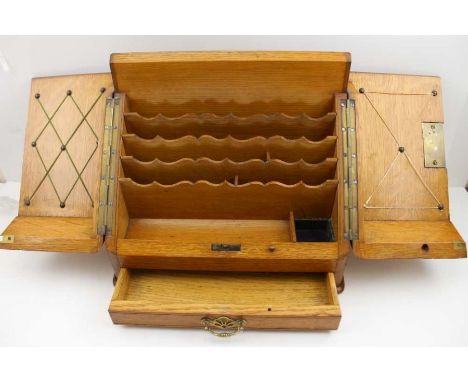 An oak table top stationery cabinet, the two door slope opens to reveal, pen tray, inkwell stand, and fitted interior, with d