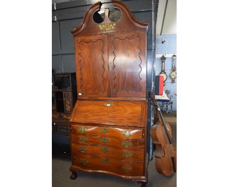 A large 18th Century American bureau bookcase, the top section with swept broken arch pediment over two panelled doors the ba