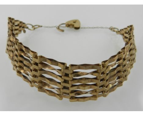 A 9 carat yellow gold six bar gate bracelet, with suspended heart-shaped locket clasp, stamped 375. 