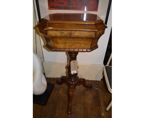 An early Victorian burr walnut octagonal topped teapoy, the hinged top enclosing two covered canisters, raised on a turned co