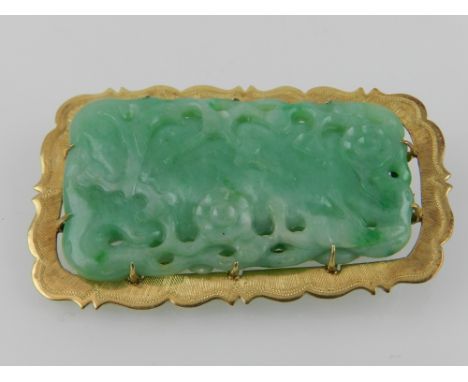 A yellow metal mounted and jade brooch, the carved rectangular jade of naturalistic design, the mount stamped 750 to verso. 