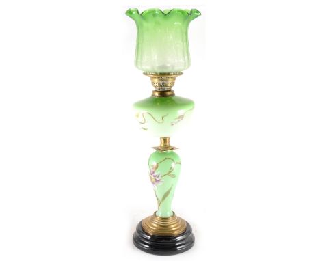 A green tinted opaque glass oil lamp, with brass fitments, enamelled floral decoration, with green tinted shade complete with