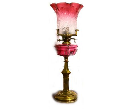 A brass based oil lamp, ruby glass reservoir, tinted ruby shade complete with chimney, 73m.