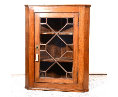 A Victorian elm hanging corner cupboard, with glazed panelled door enclosing serpentine shelves, height 99cm.