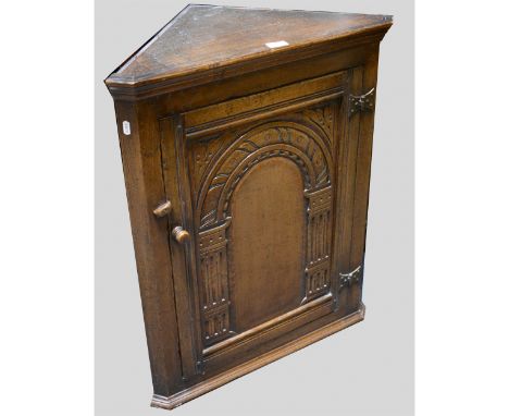 A reproduction oak hanging corner cupboard, labelled Maple, arcaded carved panel door, enclosing a single shelf, height 77cm.