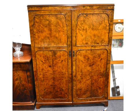 A figured walnut compactum wardrobe, two panelled doors, bracket feet, width 130cm