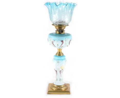 A blue opaque glass oil lamp, moulded and enamelled decoration, brass plinth and mounts, blue tinted shade complete with chim