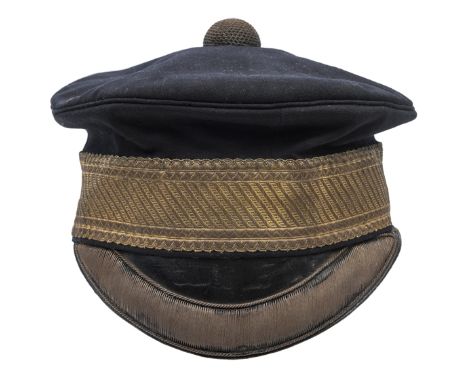 An officer’s blue cloth peaked forage cap, gilt lace headband, bullion edging to black patent leather peak and domed top butt