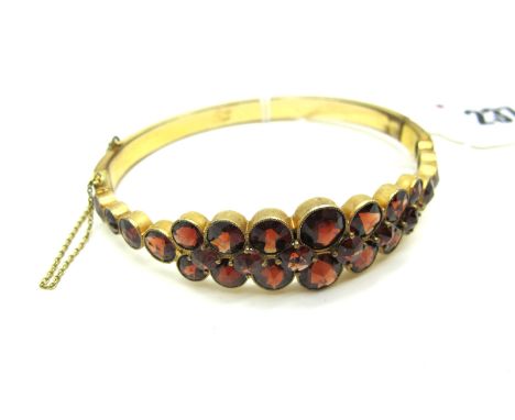 A XIX Century Style Garnet Set Bangle, graduated collet and clasp set to the front, hinged to snap clasp (internal diameter 6