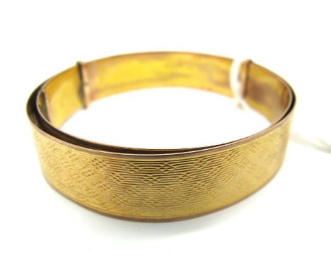 An Expandable Bangle, with allover engine turned design, stamped "9ct E A P" (15grams).