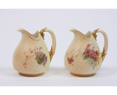 A pair of Royal Worcester jugs, of shell shape having painted floral spray decoration on a blush ivory ground, the handles wi