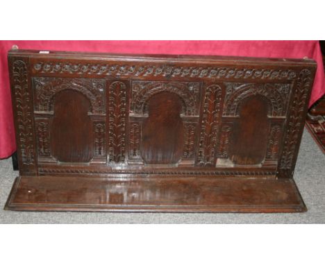 An Antique carved oak wall panel/shelf, having triple arched panels and foliate decoration, 132cm wide x 64cm high