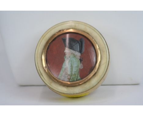 An 18th Century ivory circular snuff box, with tortoiseshell interior, the lid painted with a figure of a young boy in tricor