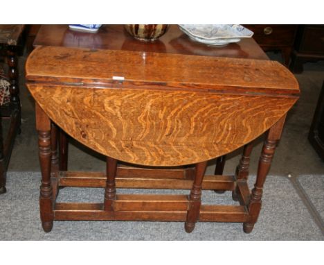 An Antique oak gate leg dining table, the oval top raised on turned baluster supports and square stretchers, 100cm x 92cm ext