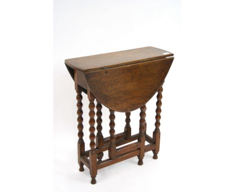 An oak gate leg tea table, raised on bobbin turned supports, 59cm x 63cm extended