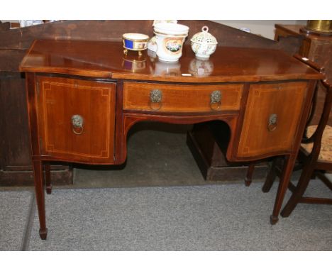 An Edwardian inlaid mahogany bow fronted sideboard, fitted central drawer above an arched frieze flanked by deep drawers and 