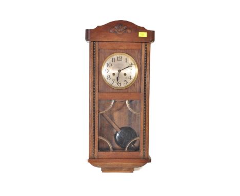 An early 20th century circa. 1920'as oak wall clock having beaded decoration having carved pediment over a silvered face with