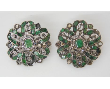 A PAIR OF EMERALD AND DIAMOND BROOCHES the gems set into white metal mounts with yellow metal pins and clasps. The emeralds a