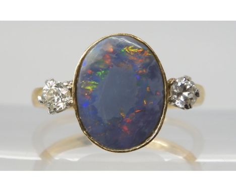 A BLACK OPAL & DIAMOND RING set with an estimated approx 12.5mm x 10mm x 3.1mm, black opal, flanked by tow estimated approx 0