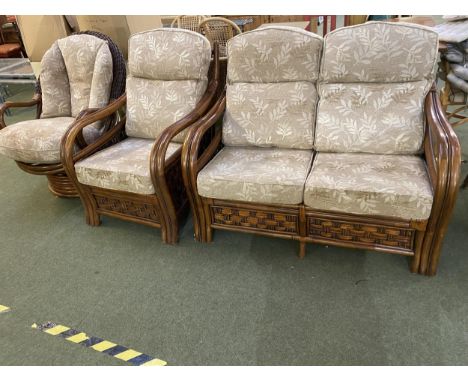 A dark brown cane sofa and chair suite, with loose cushions,  tilting and revolving arm chair 