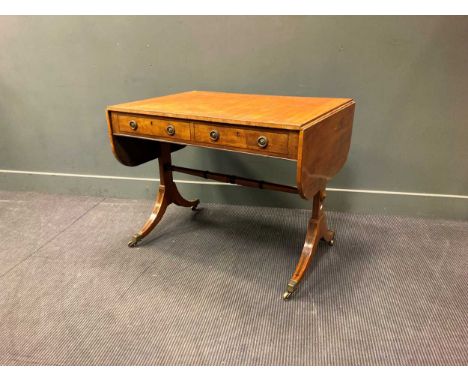 A Regency mahogany and ebony strung sofa table, with beaded brass ring handles, the frieze fitted with two drawers, on trestl