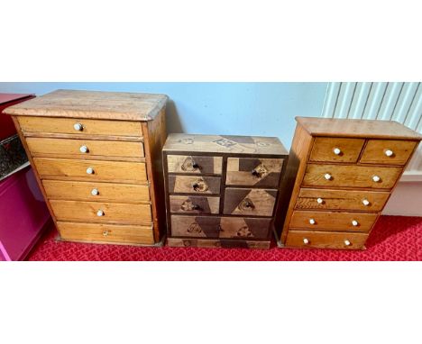 Two miniature pine chests of drawers with white ceramic knobs together with a marquetry miniature chest.