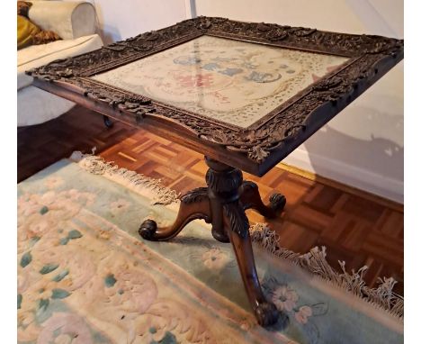 A 19thC pedestal table, cross stitch embroidery to top with intricately carved frame. 61cm h x 60cm w x 66cm d.