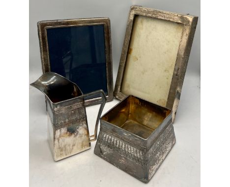 Two hallmarked silver photograph frames and an Orivit Art Nouveau silver plated jug and sugar bowl. Largest frame 17cm x 12cm