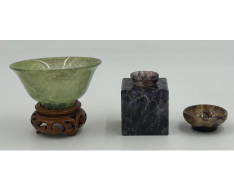 A Chinese jade small bowl on a wooden stand, 9.8cm diameter, height 4.8cm (excluding stand) together with a purple gemstone c