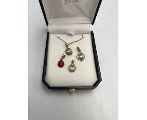 Four 9 carat gold pendants, three set with pale blue stones, one with 9 carat gold chain and a ladybird 9 carat gold and enam