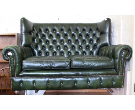 A dark green leather wingback Chesterfield style two seater sofa