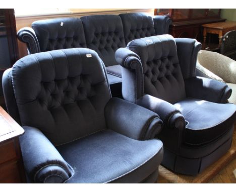 A blue velour button back three piece suite comprising a three seater sofa and two armchairs