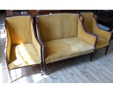 An Edwardian mahogany salon suite with mustard velvet upholstery and inlaid decoration comprising a two seater sofa and two c