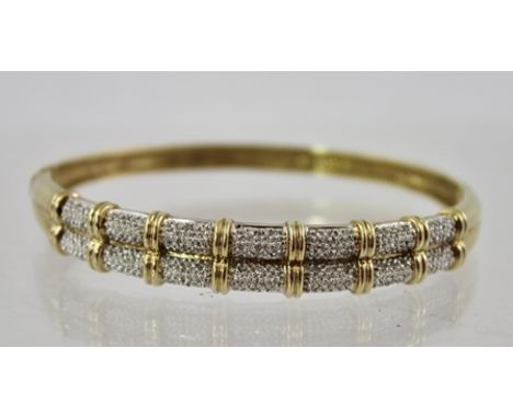 A DIAMOND AND GOLD COLOURED METAL BANGLE the top with twin rows of small diamonds and snap clasp, stamped 0.50 