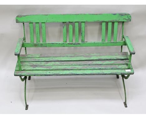 AN EDWARDIAN CHILD'S GARDEN BENCH, wrought iron and wooden lathe of open arm design, green painted, 90cm wide, back 64cm high