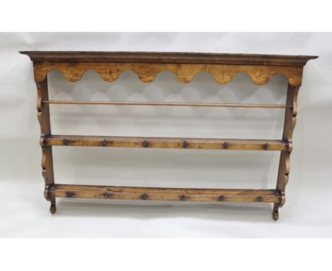 A GEORGIAN DESIGN OAK WALL RACK having shaped frieze and sides, with top shelf retaining bar and metal cup hooks, 139cm wide 