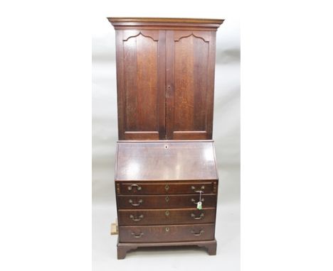 A GEORGE III OAK BUREAU BOOKCASE, the top fitted two arched panel doors, over a base with writing slope opening to reveal a f
