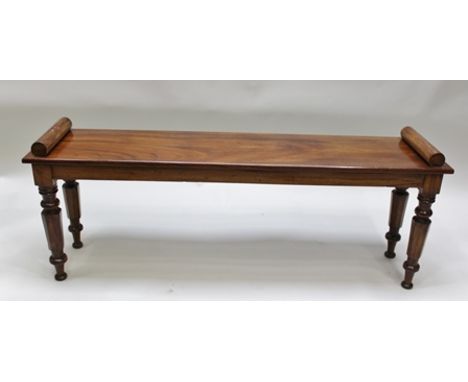 A 19TH CENTURY MAHOGANY HALL BENCH/WINDOW SEAT having turned ends raised on turned and tapering hexagonal supports 