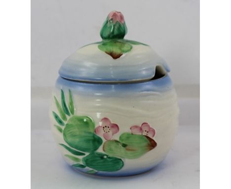 A CLARICE CLIFF JAM POT with cover, having moulded body with hand painted waterlily decoration, with a waterlily bud knop to 