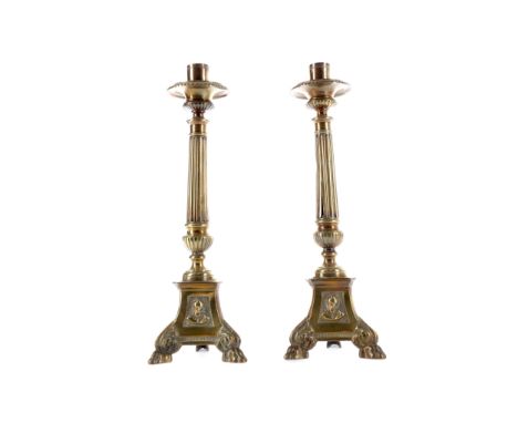 PAIR OF LATE VICTORIAN BRASS CANDLESTICKS, with gadrooned drip pan over a fluted tapered column, on tripartite bases cast in 