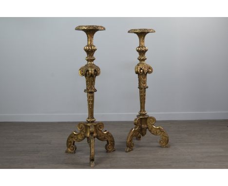 PAIR OF 19TH CENTURY BAROQUE STYLE GILTWOOD TORCHERES, the circular top on scroll, husk and lobe moulded tapering column, wit