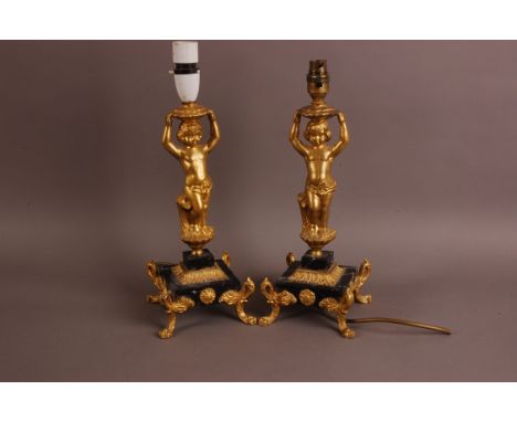 A pair of early 20th century continental figural lamp bases, having gilt figures of young boys on square marble bases with gi